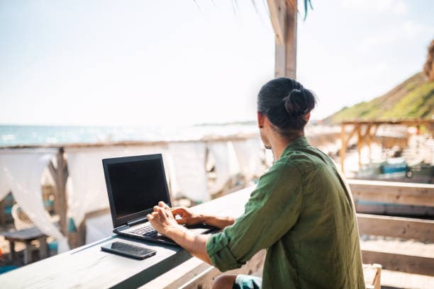 A traveler reviews a route brief beside a small carry-on in a bright city cafe.